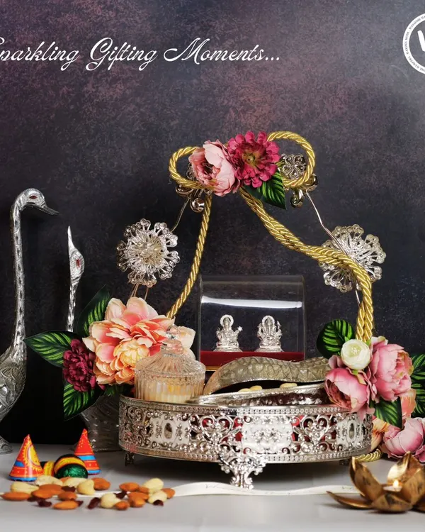 A truly luxurious festive hamper designed to make a statement. This silver-plated tray holds auspicious silver Lakshmi-Ganesh idols, premium nuts, and a decorative candle, all brought together with intricate floral arrangements for an unforgettable Diwali gift.