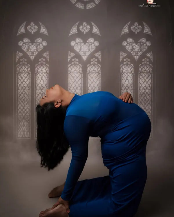 This is a powerful camel pose from a prenatal yoga session. It beautifully showcases the mother's flexibility and strength, with the artistic window-like lighting adding a spiritual feel.
