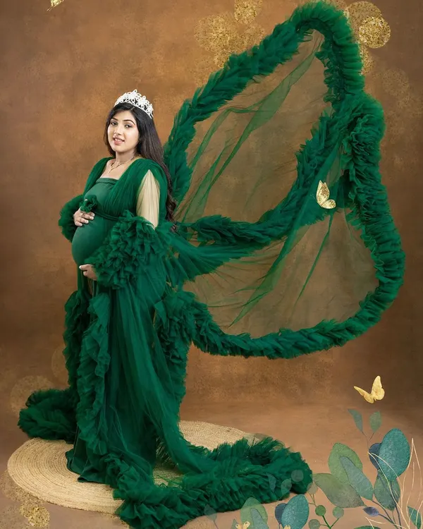 Feel like a queen in this dramatic portrait. The emerald green ruffled gown with its wing-like fabric toss and a delicate tiara creates a truly majestic and unforgettable look.
