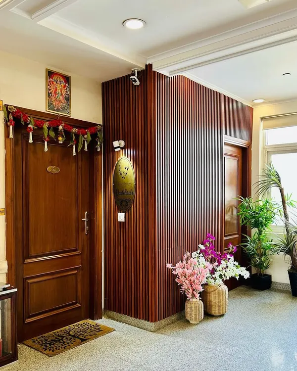 I designed this entryway to be warm and welcoming, using vertical wood fluting to add texture and warmth. The space is personalized with a custom nameplate and softened with potted plants and decorative flowers, creating an inviting first impression.