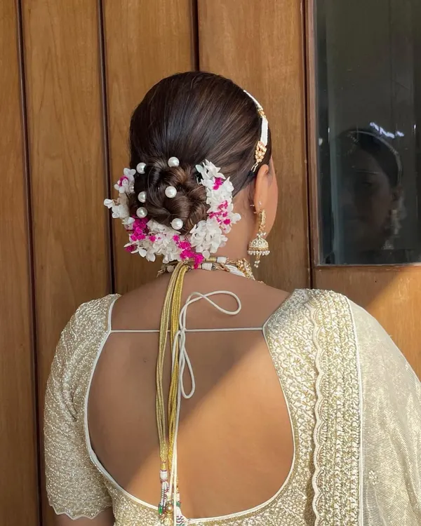 This stunning bridal bun combines fresh hydrangeas and delicate pearls for a look that is both classic and unique. It's a perfect choice for a bride wearing an all-white or pastel lehenga.