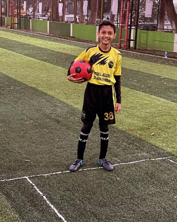 A young player poses with a ball, full of confidence after a great training session.