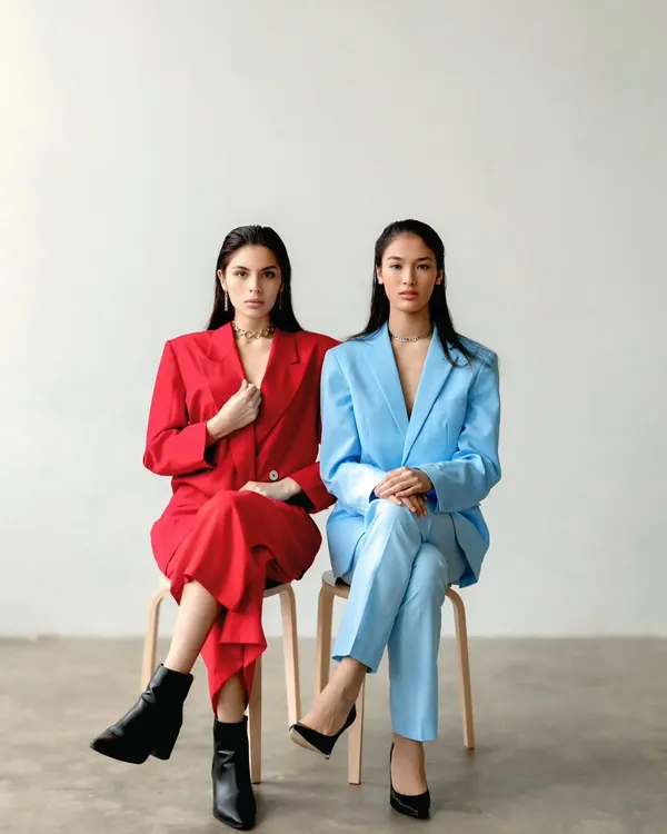 Two models, one in a red suit and one in blue, sit side-by-side, creating a powerful image of contrast and symmetry. This is a perfect example of a conceptual brand shoot.