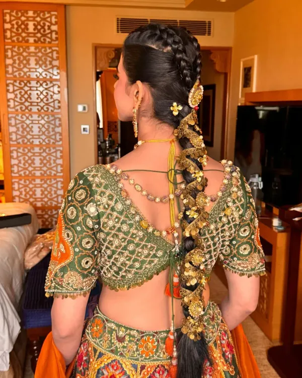 A detailed view of a traditional bridal braid, intricately woven and adorned with elaborate gold hair jewellery. This style is designed to be secure and stunning, perfectly complementing a heavily embroidered lehenga for the main wedding ceremony.