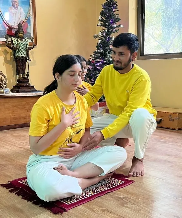 Guiding a student in a pranayama class to ensure correct hand placement and breathing technique. Proper form is essential to experience the full benefits of controlling the prana, or life force.