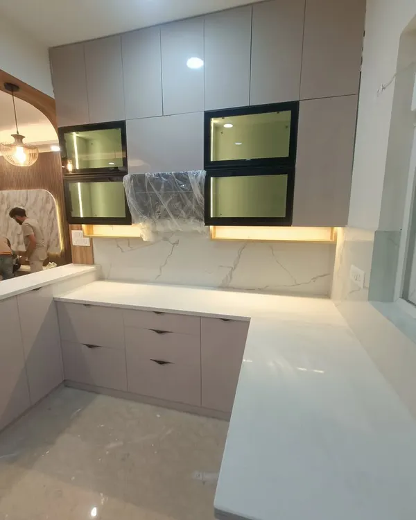 A look at a modular kitchen in progress at our ATS Rhapsody site. This U-shaped kitchen features a quartz countertop and backsplash, with under-cabinet lighting to illuminate the workspace.