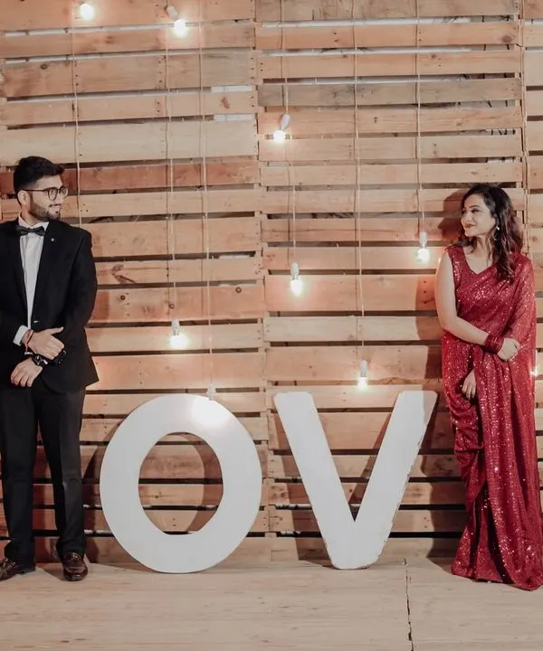 Our 'LOVE' marquee letters set against a rustic wooden wall with hanging bulbs. This is one of our most popular setups for romantic evening shoots.