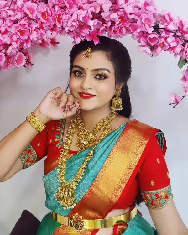 A classic South Indian festive look, complete with a bright red lip, defined eyes, and traditional gold jewelry. This makeup is designed to be radiant and picture perfect for any celebration.
