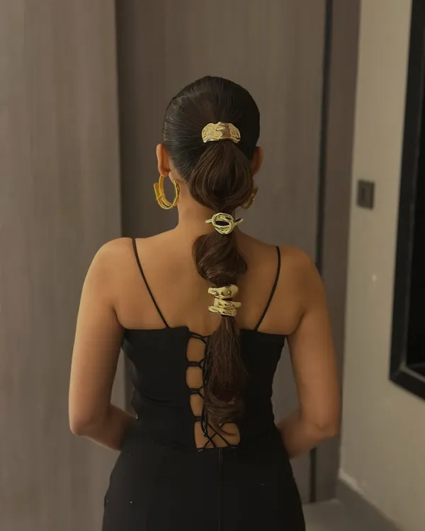 A full view of the bubble ponytail with gold accessories. This modern hairstyle is perfect for making a fashion-forward statement at parties or events.