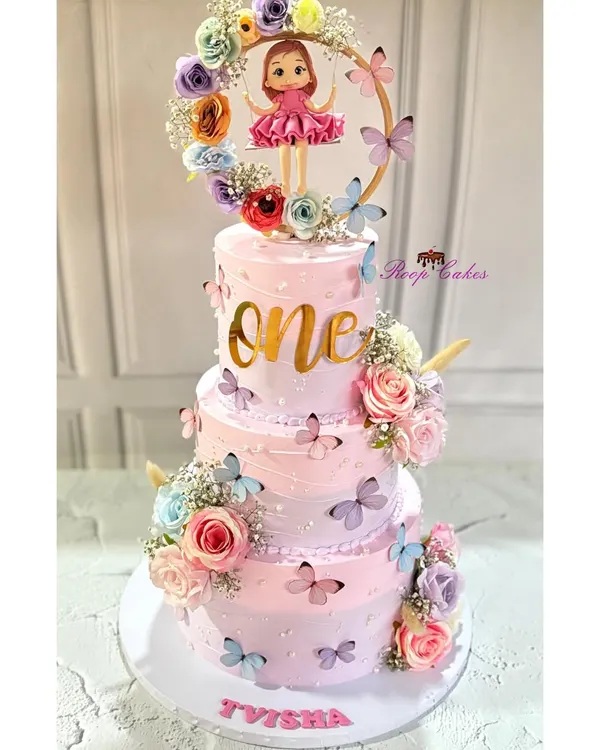 A magical three-tier "One-derland" cake for Tvisha's first birthday. This pink creation is decorated with butterflies, flowers, and a beautiful topper featuring a doll in a floral hoop.