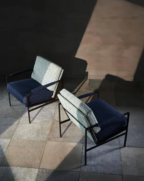 Two modern armchairs captured from above, with dramatic lighting highlighting their form and texture. This artistic shot focuses on the interplay between light, shadow, and upholstery.