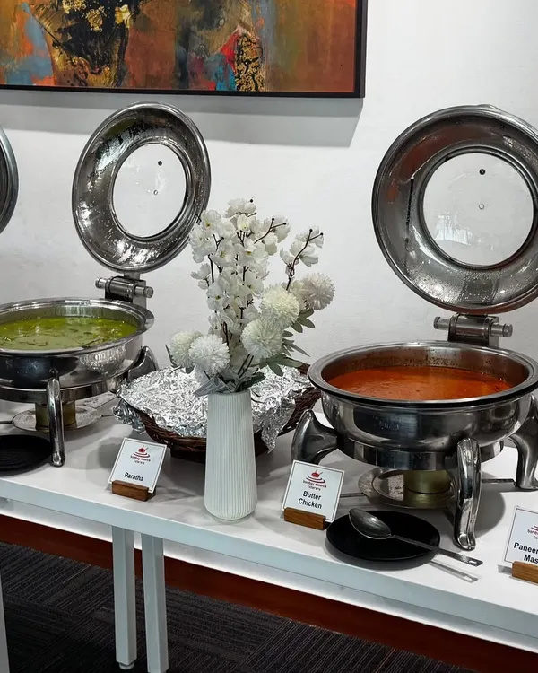 A professional buffet line we organized for a corporate lunch. The setup features a variety of main courses in stainless steel chafing dishes, clearly labeled for guests, ensuring an organized and high-quality dining experience.