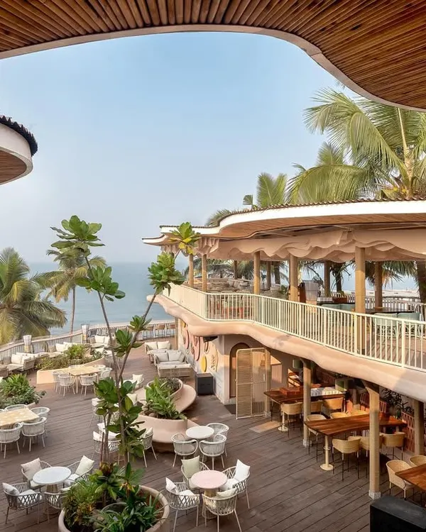 An elevated view of Dubki, showing how the organic, wave-like roof structure frames the stunning ocean view. The multi-level design provides various seating areas, all oriented towards the sea.