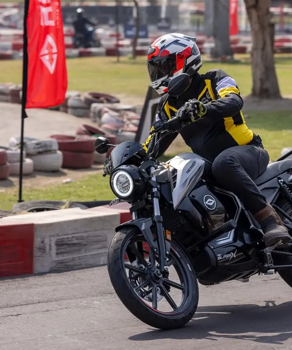 An action shot of the Revolt electric motorcycle cornering on a racetrack. Capturing the bike in motion with a rider in full gear adds a sense of speed and performance.