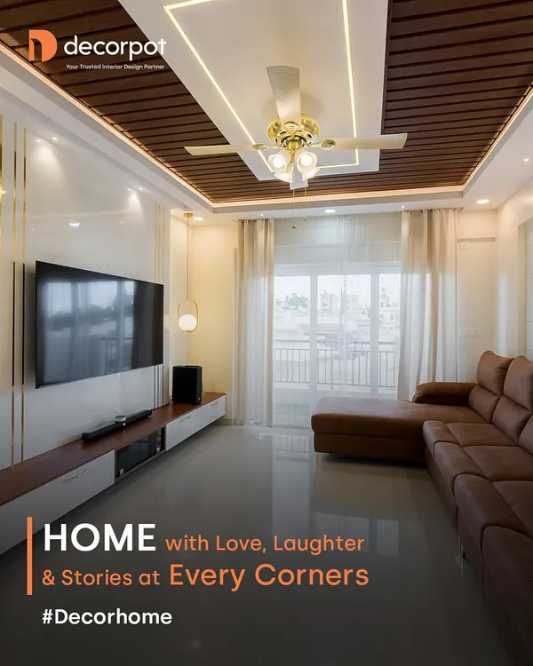 This is the feeling of home we strive to create. A bright, elegant living room with a comfortable L-shaped sofa, a modern false ceiling with wooden accents, and ample natural light, making it the perfect space for family and stories.