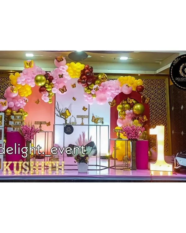 We love bringing big themes to life, like this butterfly-themed first birthday party. This grand setup includes a multi-colored balloon arch, decorative pedestals for the cake, light-up letters for the baby's name, and a large marquee number '1'.
