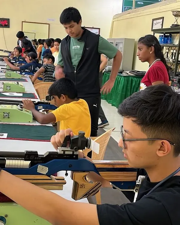 A young shooter takes aim with a competition-grade air rifle under the watchful eye of an instructor. I focus on teaching proper form and concentration from the very first session.