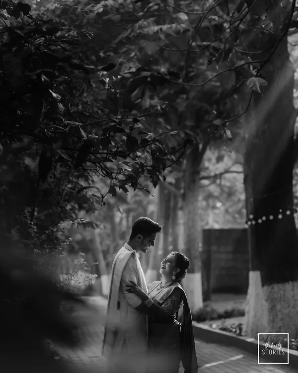 A classic black and white shot, beautifully lit by a ray of sun. This image has a timeless, cinematic quality, focusing entirely on the couple's romantic interaction.