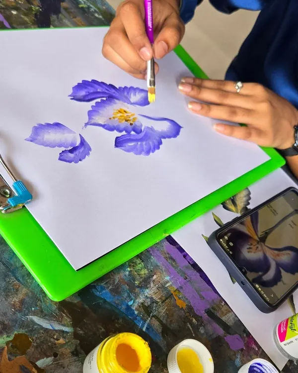 A student practices the one-stroke painting technique to create delicate flower petals. This method is fantastic for learning brush control and is used in everything from canvas art to nail art.