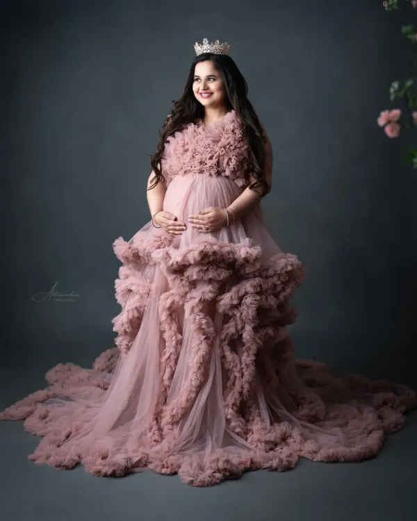 A true fairytale moment. This mom-to-be looks absolutely radiant in our ruffled pink cloud gown, complete with a crown for that perfect regal touch.