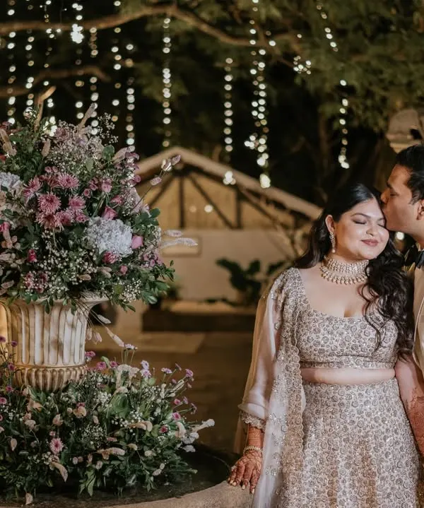 A kiss of love and appreciation. This tender moment between the couple, captured by the flower-adorned fountain, is a beautiful testament to their connection and the romantic atmosphere of their cocktail party.