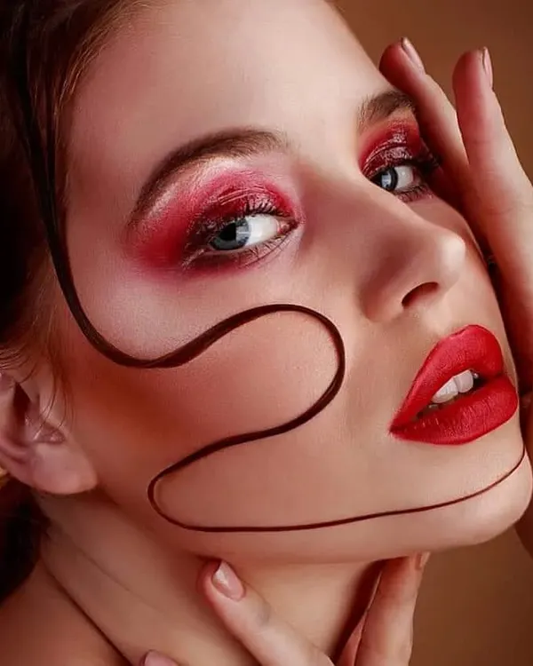 A creative beauty portrait featuring vibrant red eyeshadow and a matching bold lip. I added a graphic hair element across the face to create an artistic, avant-garde makeup statement.