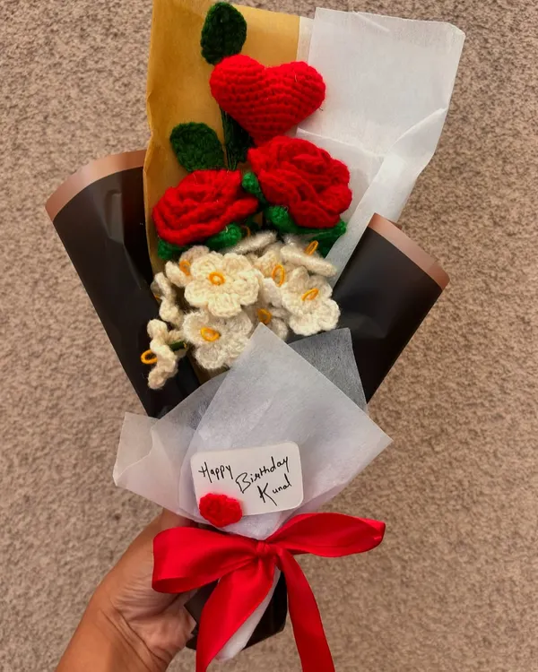 A handmade crochet bouquet created for a special birthday. This arrangement includes vibrant red roses, delicate white daisies, and a cute red heart, all tied together with a personalized "Happy Birthday" note.
