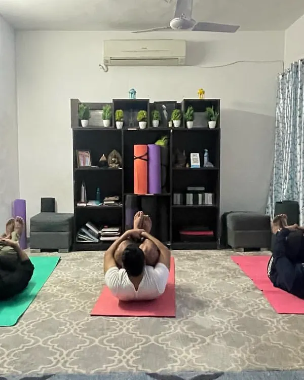 Students in my group class practicing a variation of Pavanmuktasana, the Wind Relieving Pose, to aid digestion and release tension in the lower back. The screen in the background often guides our meditation visuals.