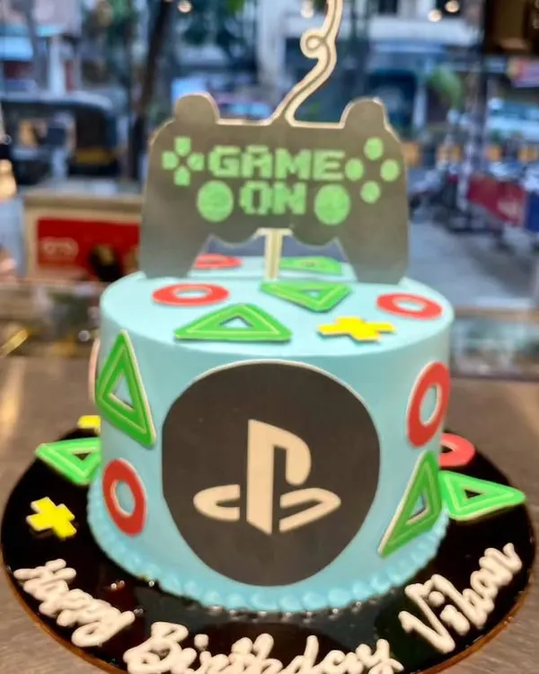 Game on! This PlayStation-themed cake is the perfect level-up for any gamer's birthday. It features the iconic controller symbols, the PS logo, and a "Game On" topper.