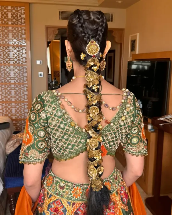 A close-up of a traditional jeweled braid, showing the detailed placement of each gold accessory. This style is built to last through long ceremonies while supporting the weight of other hair ornaments.