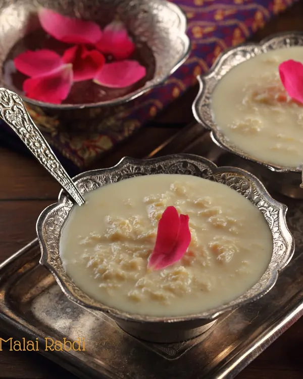 Our homemade Malai Rabdi, served in traditional silver bowls. This dessert is made by simmering milk for hours until it thickens, sweetened just right, and garnished with rose petals.