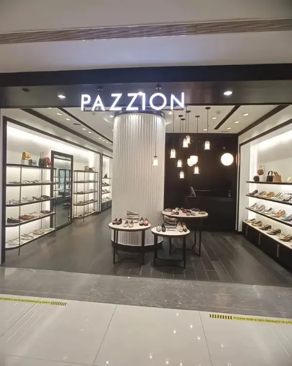 The storefront of the Pazzion luxury footwear store at DLF Avenue, Delhi. The design features a dark, sophisticated facade with a brightly lit interior to draw customers in, showcasing our ability to create inviting retail entrances.