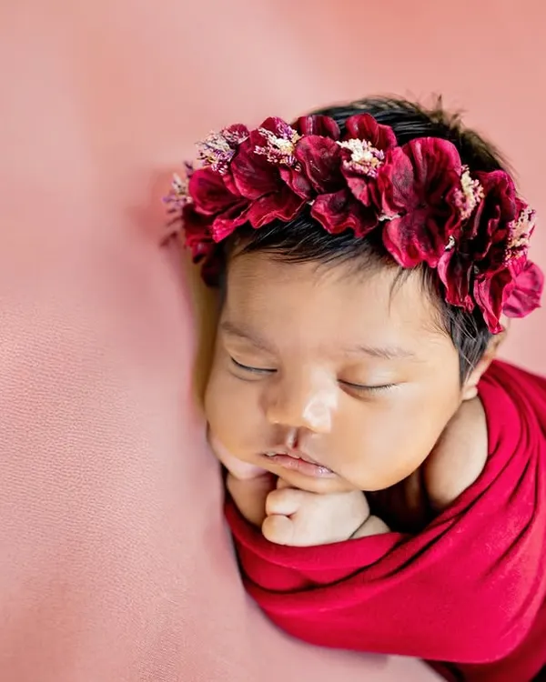 This little one looks like a beautiful rose, wrapped in red with a delicate floral crown. I use a variety of colorful wraps and props to style your newborn session.