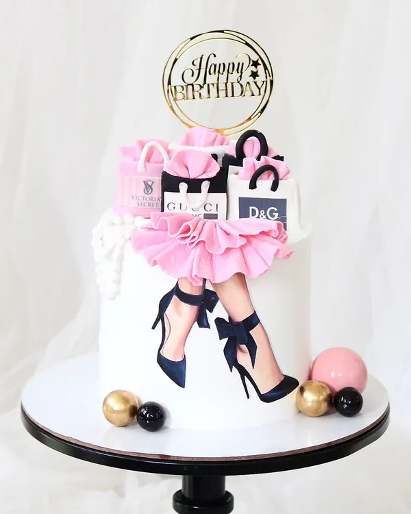 A super stylish cake for the shopaholic. This design features an edible print of fashionable legs, a pink fondant skirt, and is topped with handcrafted, miniature shopping bags from luxury brands like Gucci and D&G.
