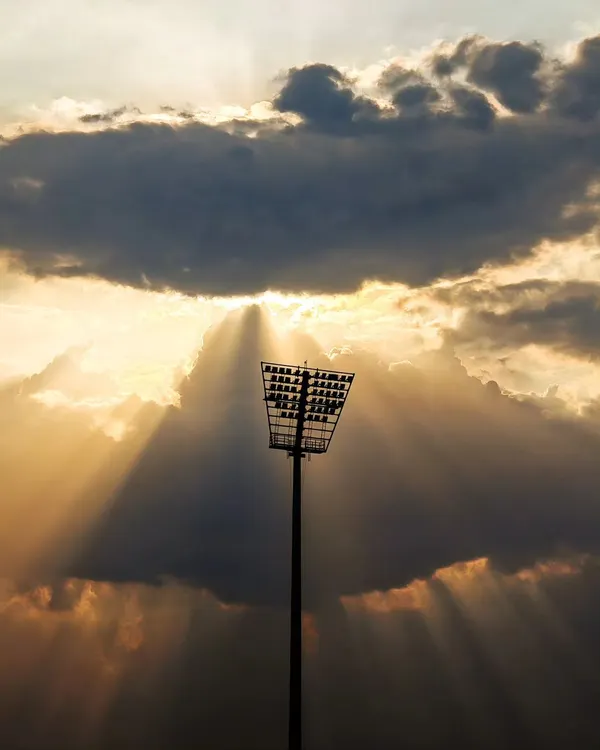 The calm before the storm. A dramatic shot of the stadium floodlights as the sun sets, building anticipation for the night's game.