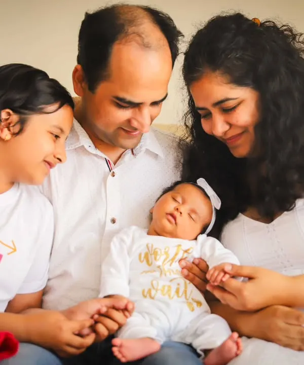 A perfect example of an at-home session. The whole family, dressed in white, admiring their new baby in the comfort of their own space.