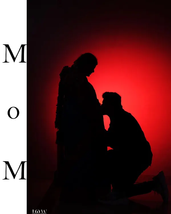 A dramatic and artistic silhouette of a man kneeling to kiss his partner's baby bump. This maternity photo captures the love and anticipation of parenthood in a powerful, visual way.
