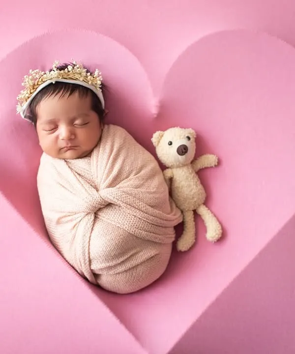 Your love, all wrapped up. A newborn sleeps peacefully inside a heart-shaped prop, a perfect symbol of a new love.