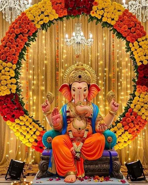 This is one of my signature Ganpati decorations. The grand circular arch made of fresh marigolds in orange, yellow, and red creates a vibrant and traditional backdrop, perfectly complemented by the warm glow of fairy lights and a grand chandelier.