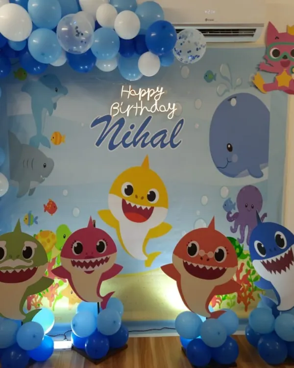 This Baby Shark party for Nihal's birthday was a dive into fun. The backdrop featured the whole shark family as cutouts against an ocean scene, framed by a blue and white balloon arch that mimics bubbles.