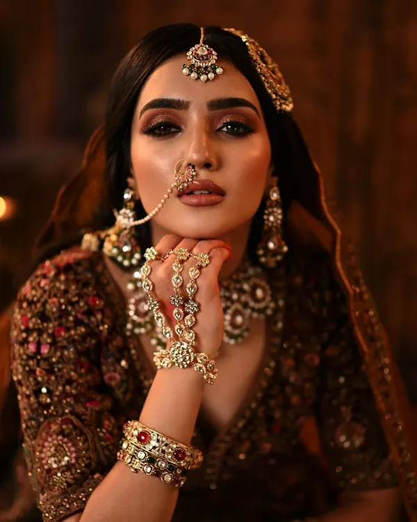 This is the level of detail and artistry I bring to every bridal makeover. This close-up on a regal maroon velvet lehenga look highlights the sharp, defined eye makeup, perfectly blended skin, and intricate jewelry placement that creates a stunning, high-impact result for your big day.