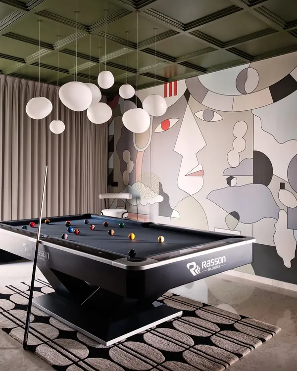 For this Bangalore home, we converted two bedrooms into the ultimate entertainment den. A professional pool table sits under a cloud of globe pendant lights, set against a dramatic, custom-designed mural wall.
