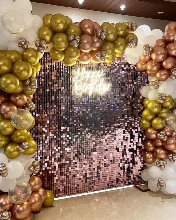 A stunning rose gold sequin wall framed by a balloon arch in gold, white, and rose gold for a glamorous birthday party.