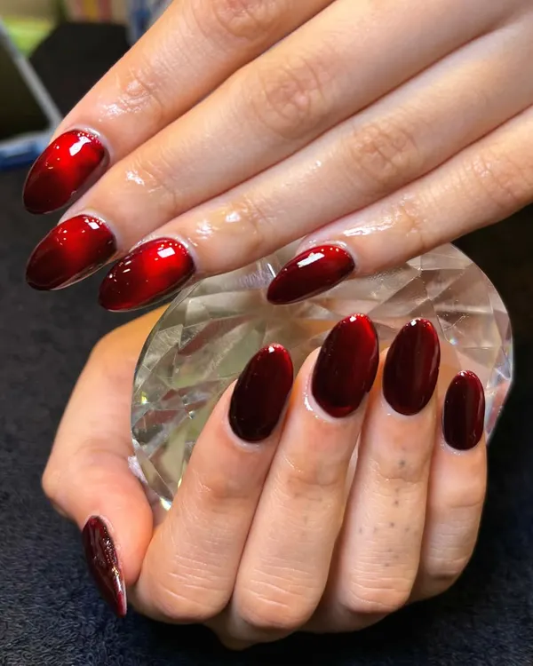 Subtle shimmer, bold statement. This is my red cat-eye nail art, which creates a stunning, dimensional effect. Here, the nails are held against a crystal to showcase their deep, velvety shine.