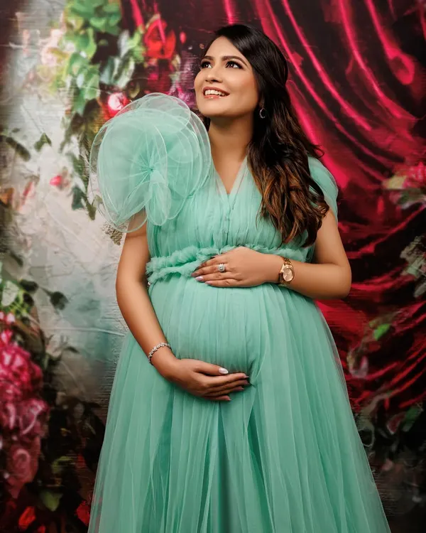 A moment of quiet reflection and anticipation. This expecting mother looks absolutely radiant in a delicate mint green tulle gown. The elegant pose, with her hands cradling her baby bump, beautifully highlights the bond between mother and child before they even meet.