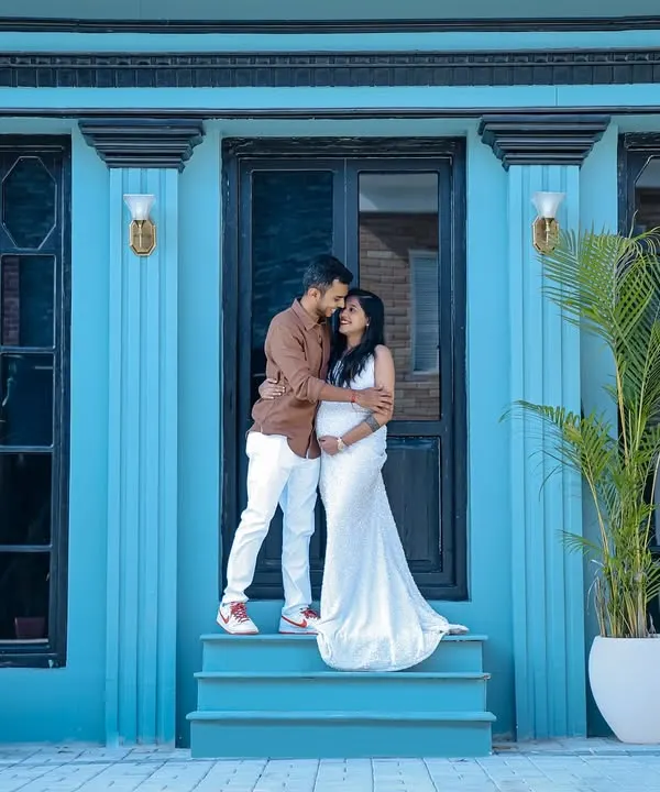A stylish outdoor couple's maternity shoot. The modern architecture with its bold blue color provides a unique and vibrant backdrop for this intimate portrait.