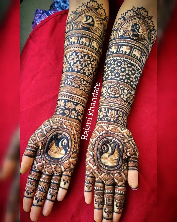 This bridal design is a symphony of traditional motifs. The palms feature elegant swans, while the arms are decorated with bands of peacocks, elephants, and intricate floral and geometric patterns.