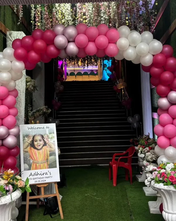 A beautiful pink and white balloon arch creating a grand entrance for a birthday party, complete with a personalized welcome sign.