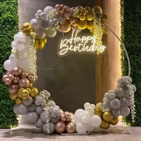 An elegant circular balloon frame perfect for birthdays or anniversaries. The mix of chrome gold, white, and rose gold balloons creates a sophisticated backdrop, beautifully finished with a neon sign.