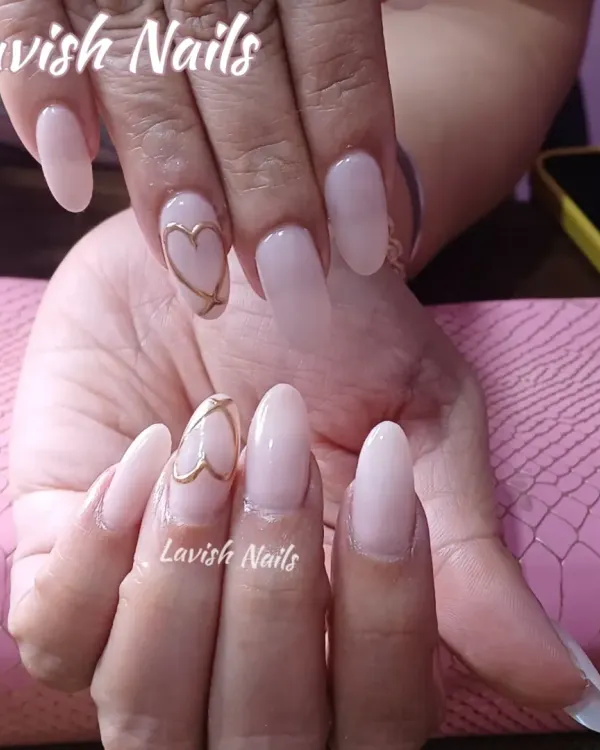 A beautiful and simple set of long, milky pink oval nails with a delicate gold heart outline on the accent nail.